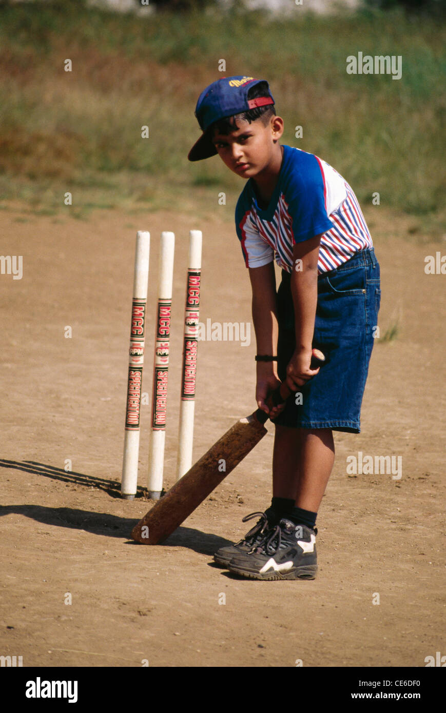 Bambino indiano battendo giocando cricket in piedi davanti a ceppi ; India ; Asia ; MR 158 Foto Stock