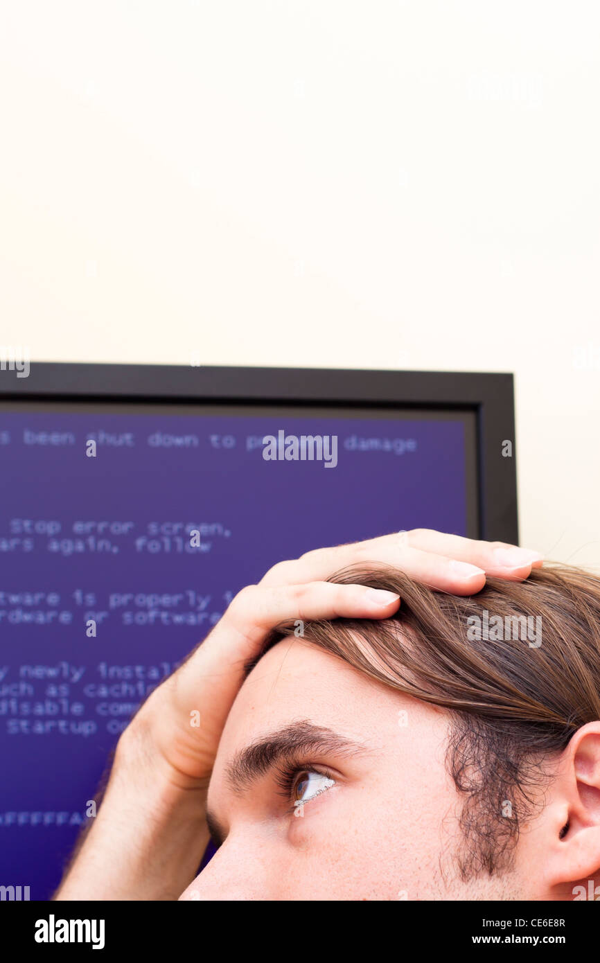 Uomo infelice guardare il computer il messaggio di errore. Schermata blu della morte. Foto Stock