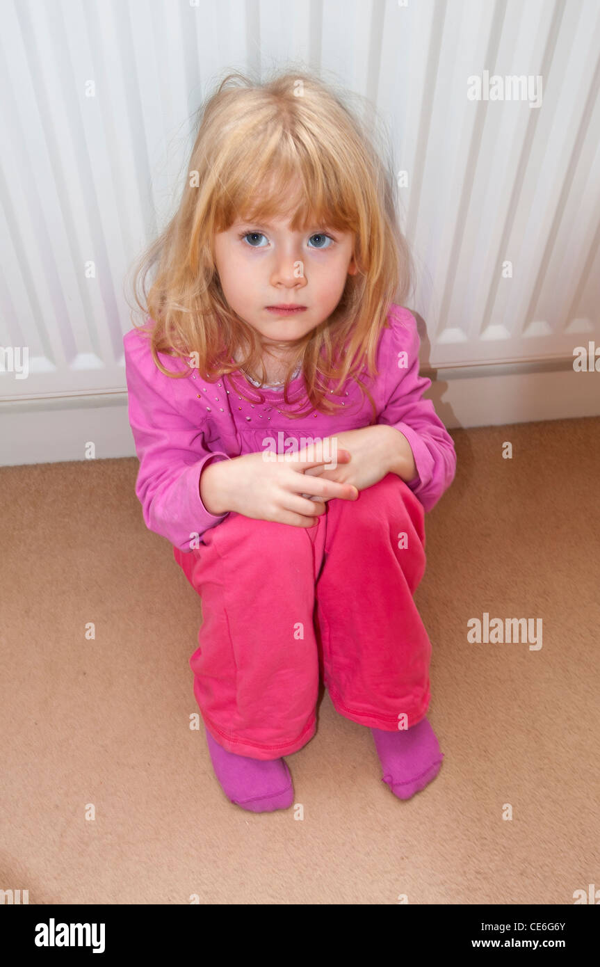 Giovane ragazza seduta sul pavimento cercando preoccupato Foto Stock