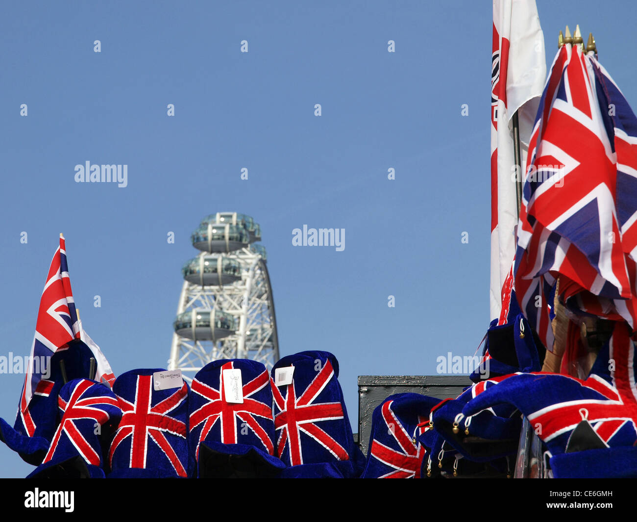Un fuori fuoco London Eye torri al di sopra di un negozio di souvenir stallo con la union jack flag e cappelli. Foto Stock