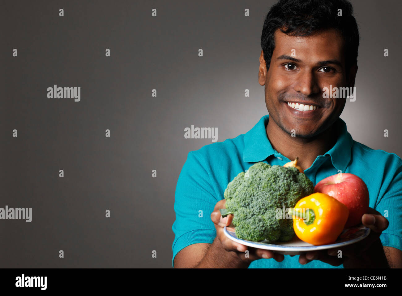 Colpo alla testa di uomo indiano piastra di contenimento di frutta e verdura Foto Stock