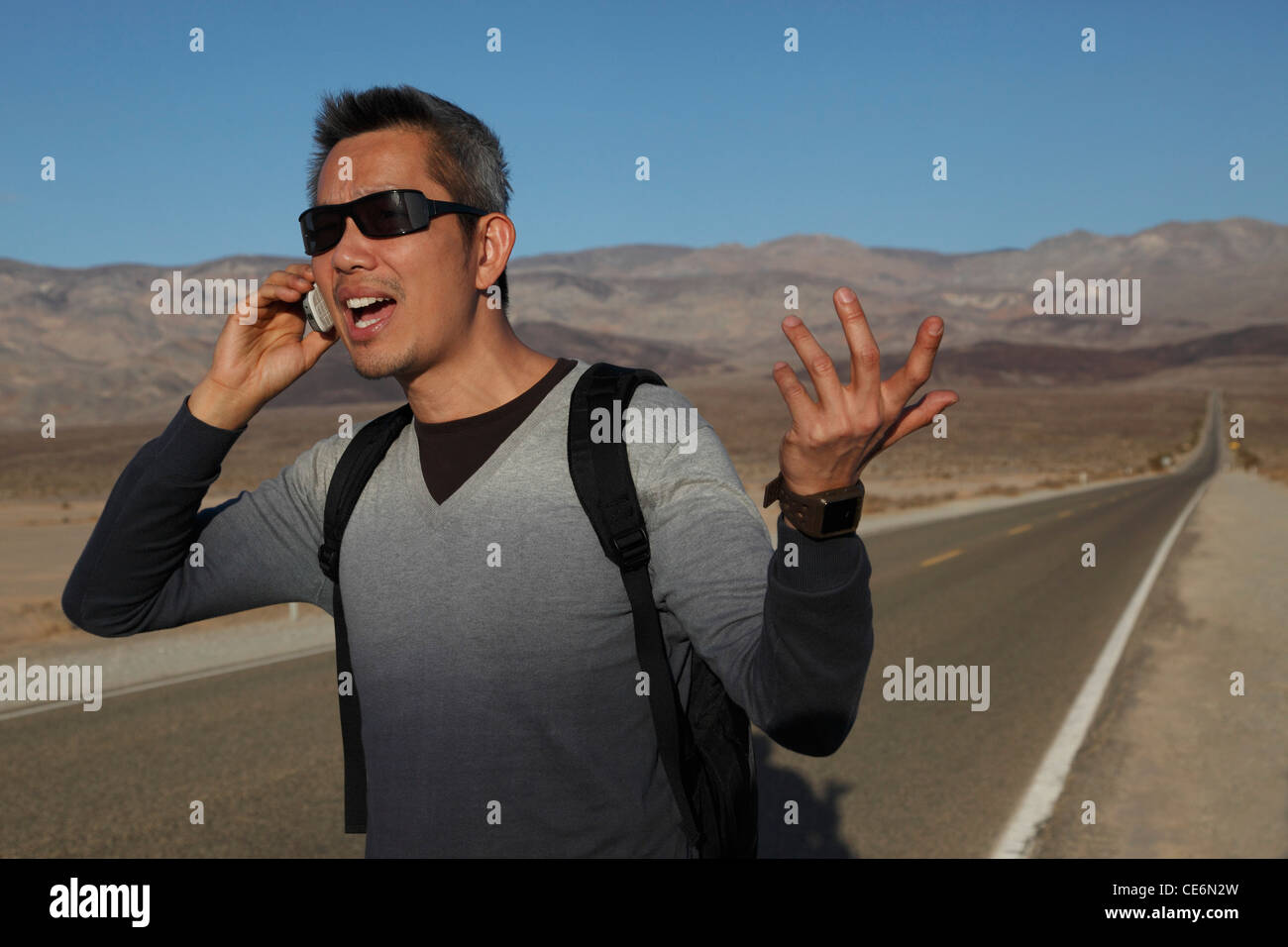 Uomo che parla al telefono sul lato della strada deserta Foto Stock