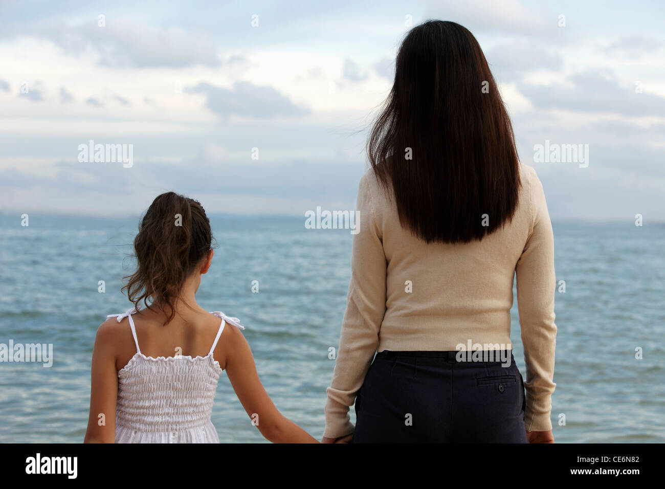 Vista posteriore della madre e figlia per mano guardando l'acqua Foto Stock