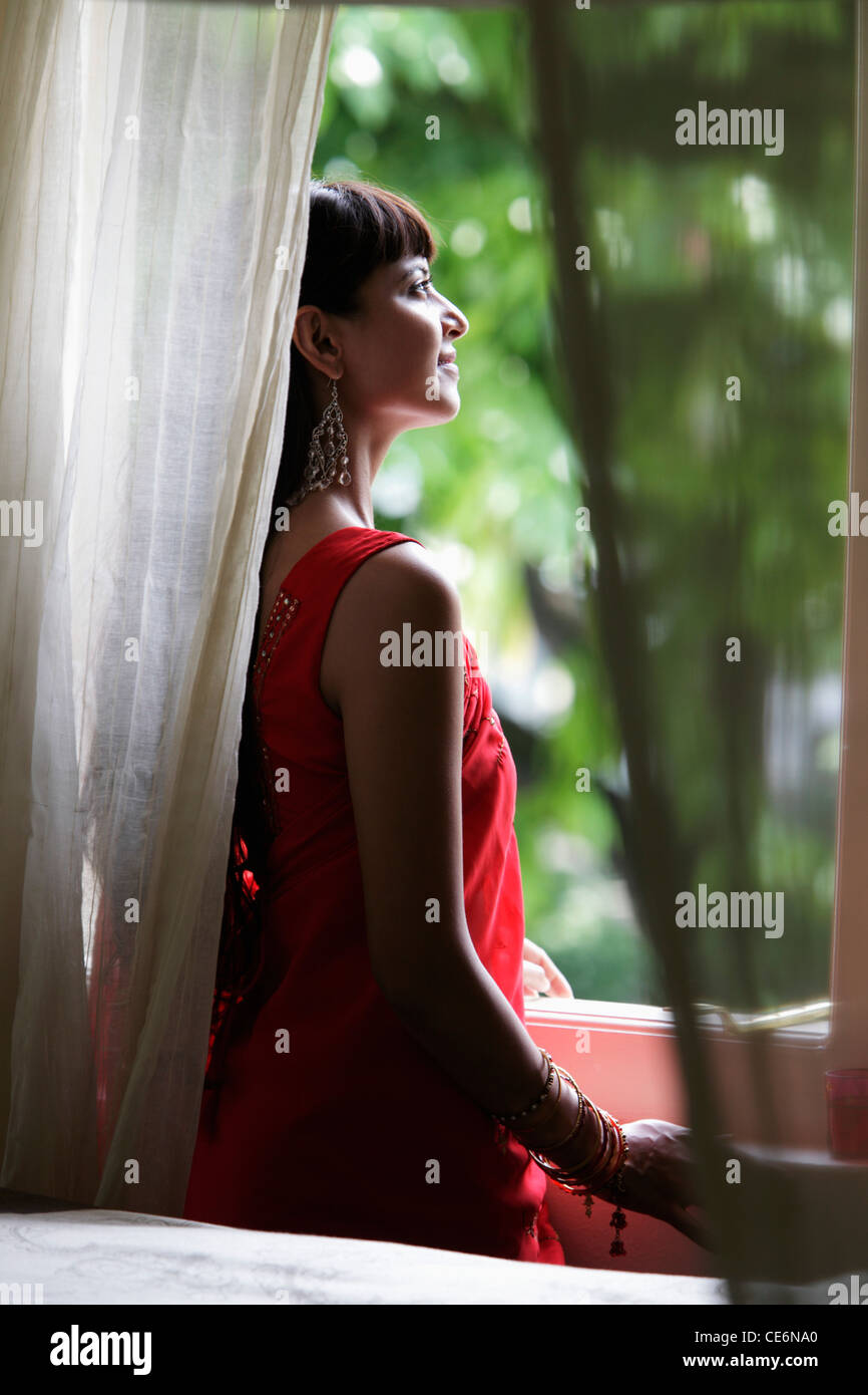 Donna indiana a guardare fuori dalla finestra Foto Stock