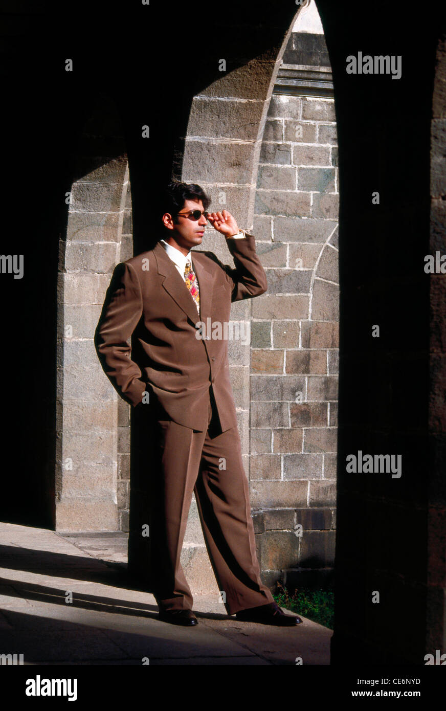 Imprenditore della tuta marrone camicia occhiali scuri in piedi in archway signor#139 Foto Stock