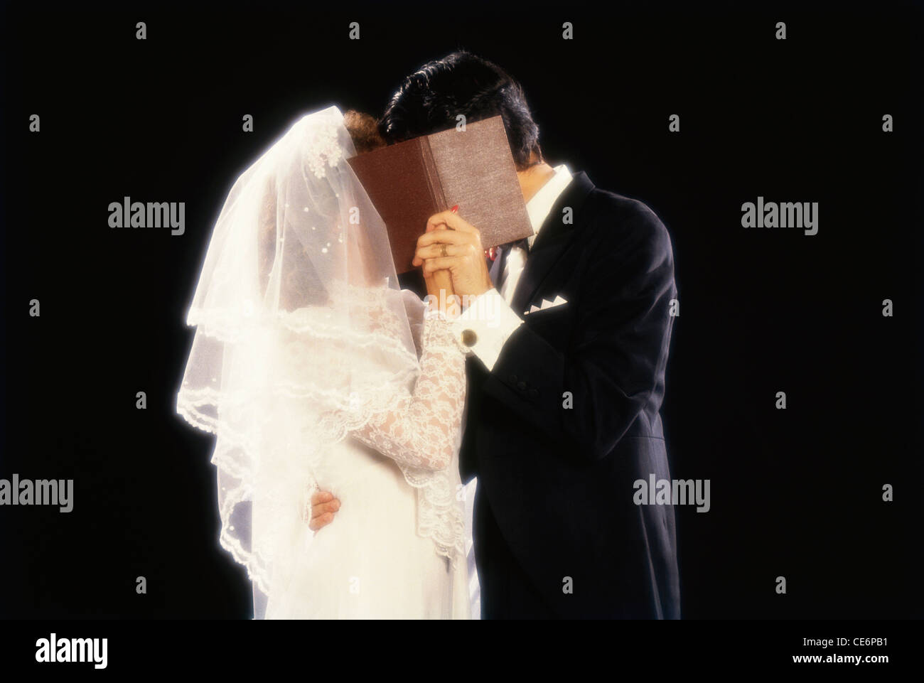 Christen sposa e lo sposo baciare nascondendo la faccia nella cerimonia di matrimonio Foto Stock