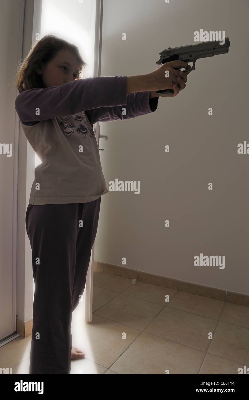 La ragazza (10) in pigiama indicando una pistola Foto Stock