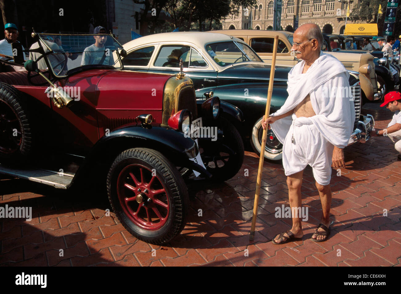 Indian vecchio uomo vestito come il Mahatma Gandhi guardando vecchi vetture d'epoca kala ghoda bombay Mumbai India Maharashtra Foto Stock