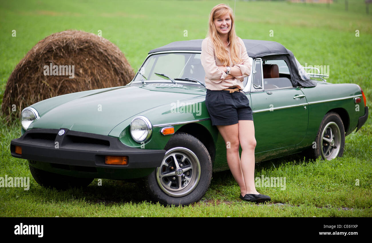 Donna appoggiata contro 1976 MGB in un pascolo. Foto Stock