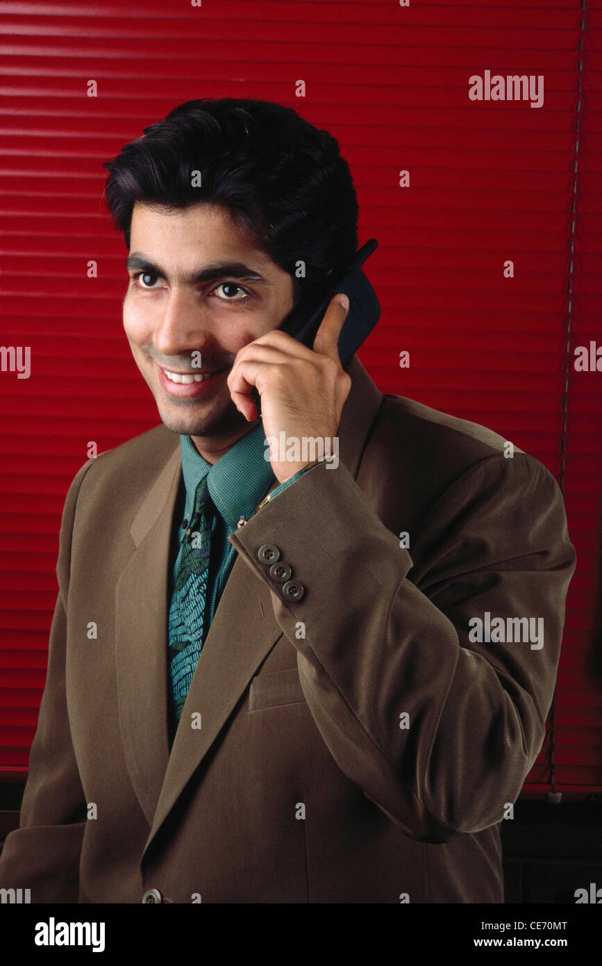 DPA 84055 : Sud Asiatico esecutivo indiano uomo Giacca marrone camicia verde cravatta parlando di telefono cellulare persiane rosse signor#139 Foto Stock