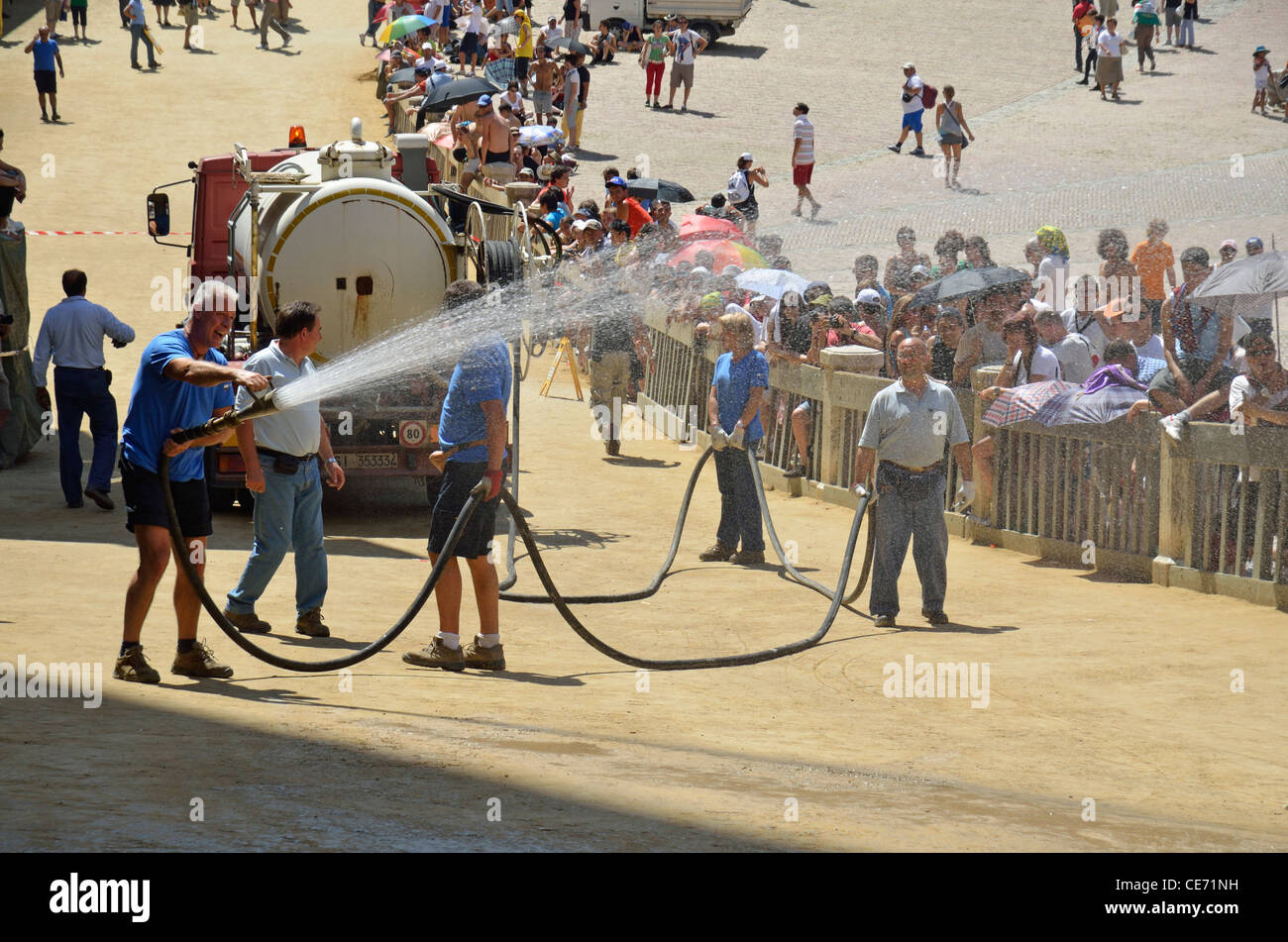 I dipendenti comunali la spruzzatura di acqua la Piazza del Campo prima della corsa di cavalli sul Palio di Siena giorno, Siena, Toscana, Italia Foto Stock