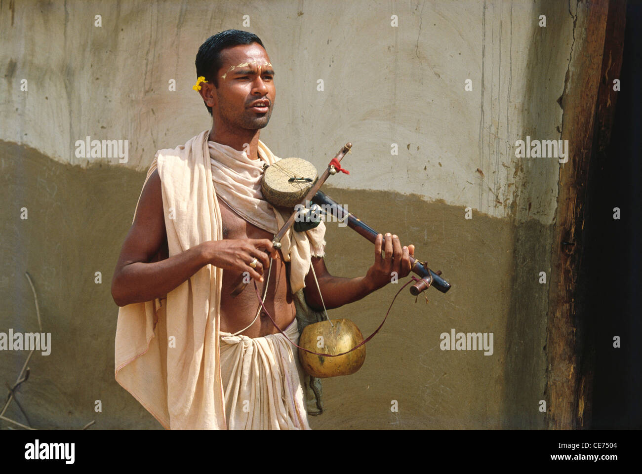 Uomo indiano sadhu sacerdote suonando uno strumento musicale d'archi ektara orissa odisha india asia Foto Stock