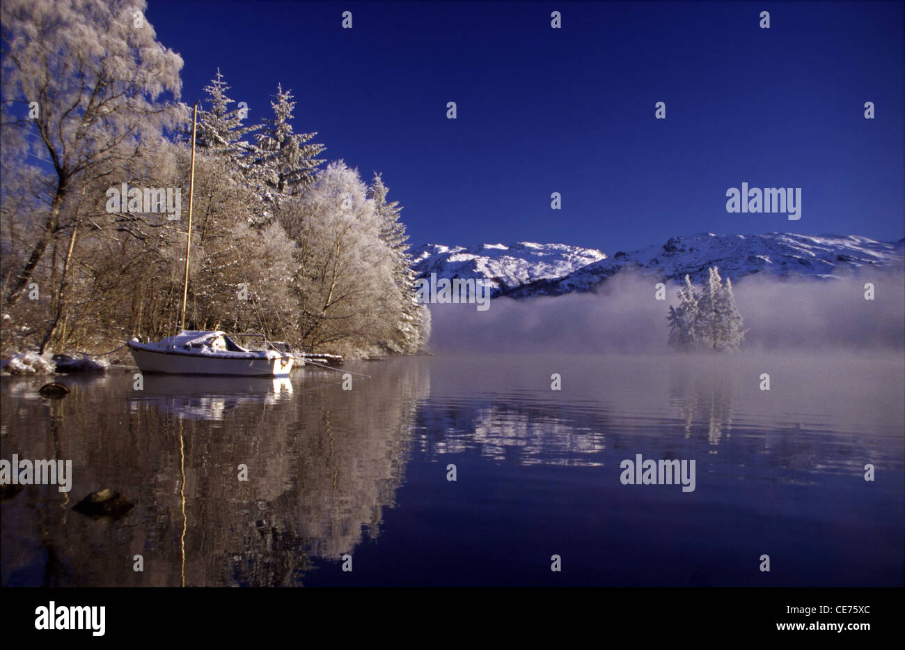 Congelati di betulle e montagne innevate riflessa sulle acque cristalline del Lago di Loch Ness e delle Highlands, Scotland, Regno Unito. Foto Stock