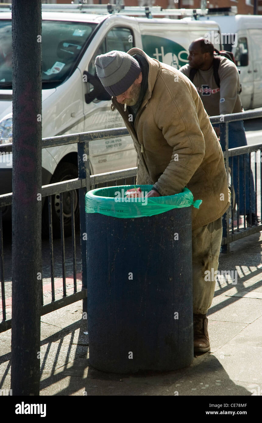 Una persona senza dimora il radicamento attraverso un bin in Brixton Foto Stock