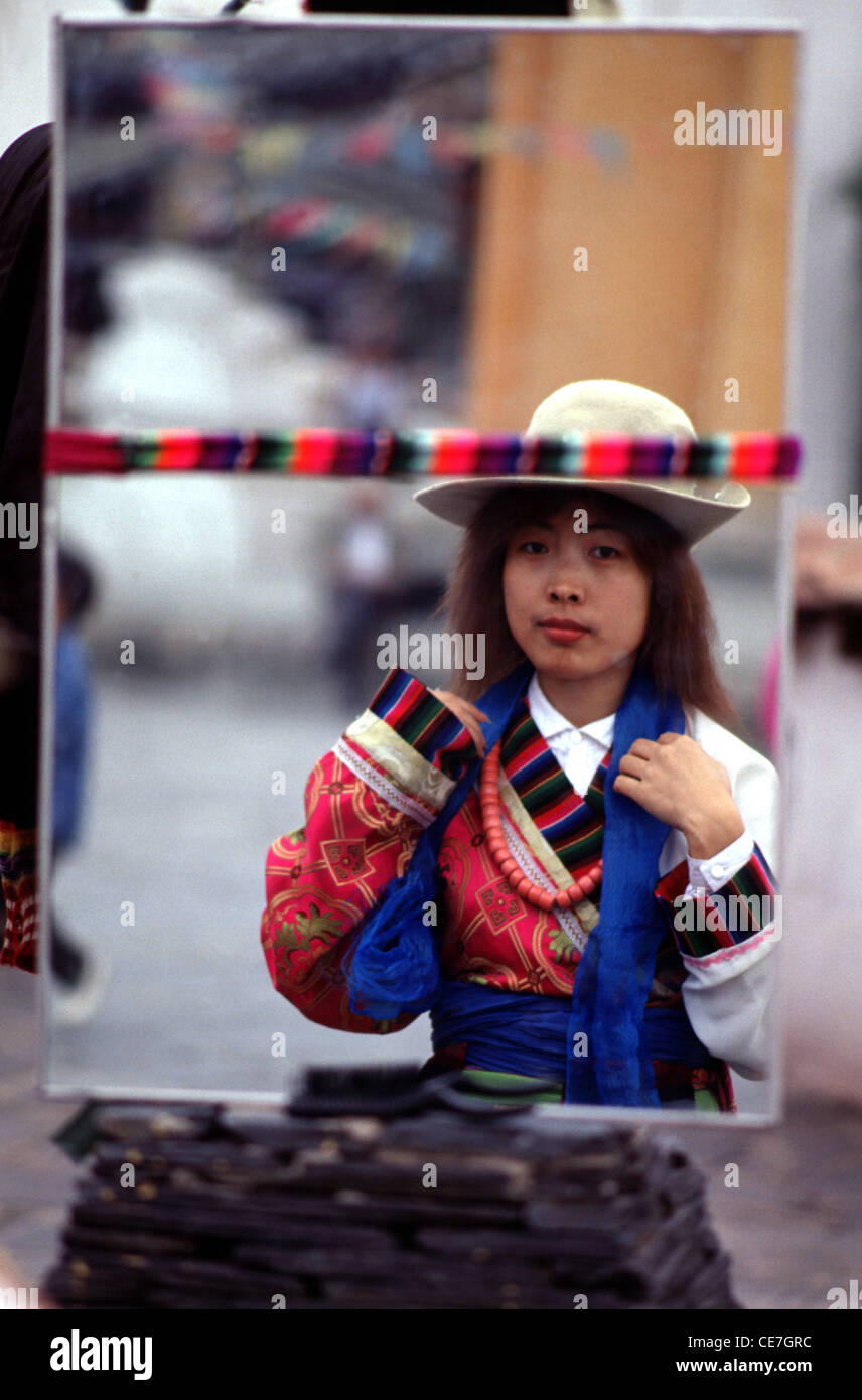 Riflessione in uno specchio di una giovane donna cinese che indossa il tradizionale costume tibetano mentre si visita il parco culturale delle minoranze etniche situato nella sezione meridionale del Parco Olimpico di Pechino Cina Foto Stock