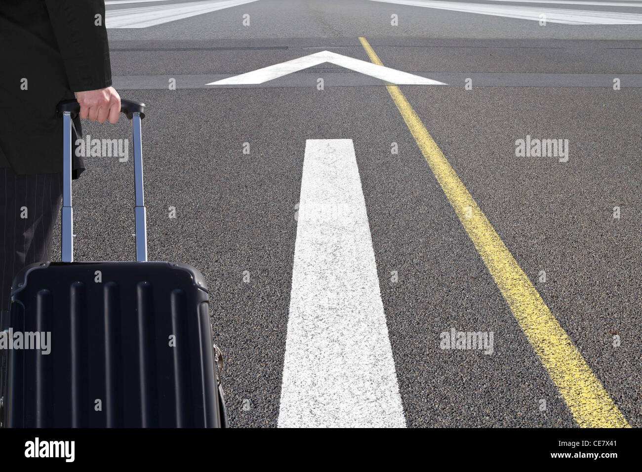 Viaggiatore con carrello scorrevole su una pista di aeroporto Foto Stock