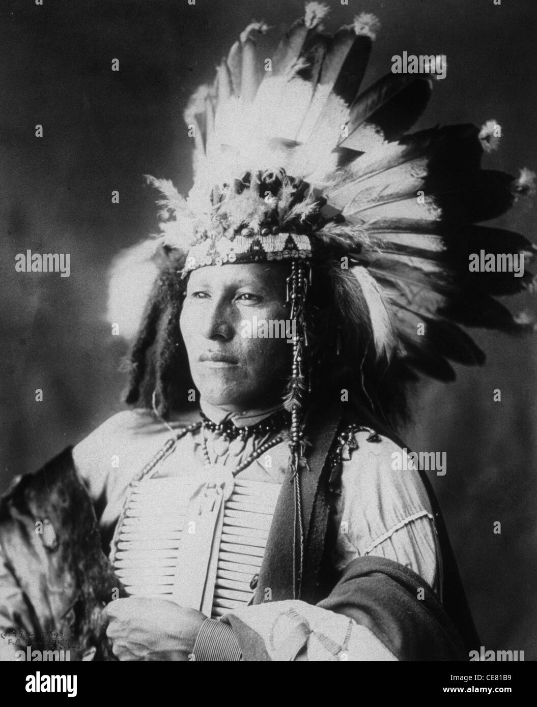 Piccolo soldato, guerriero Sioux, mezza lunghezza verticale, rivolto verso sinistra, indossando il pettorale e guerra cofano, circa 1899 Foto Stock