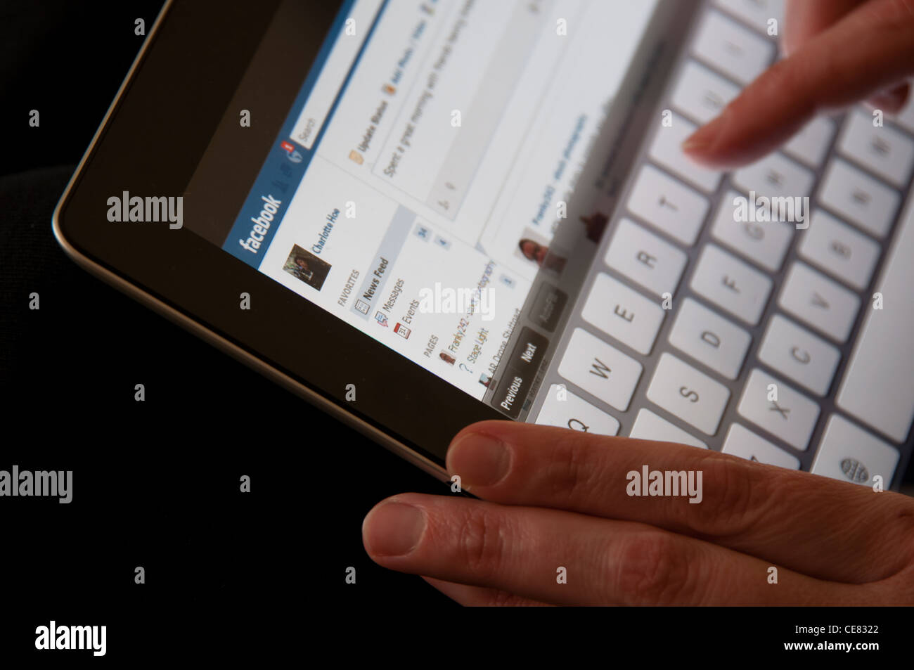 Close up di un iPad Apple schermata che mostra il sito web Facebook con mani femminili la digitazione di un aggiornamento di stato Foto Stock
