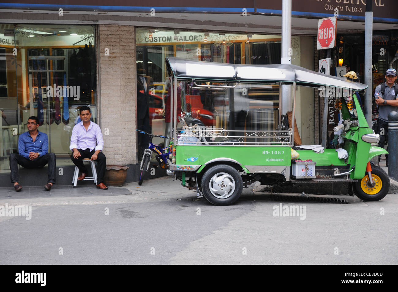 Un tuk tuk driver e in attesa su un angolo della Sukhumvit Road, Bangkok, Thailandia Foto Stock