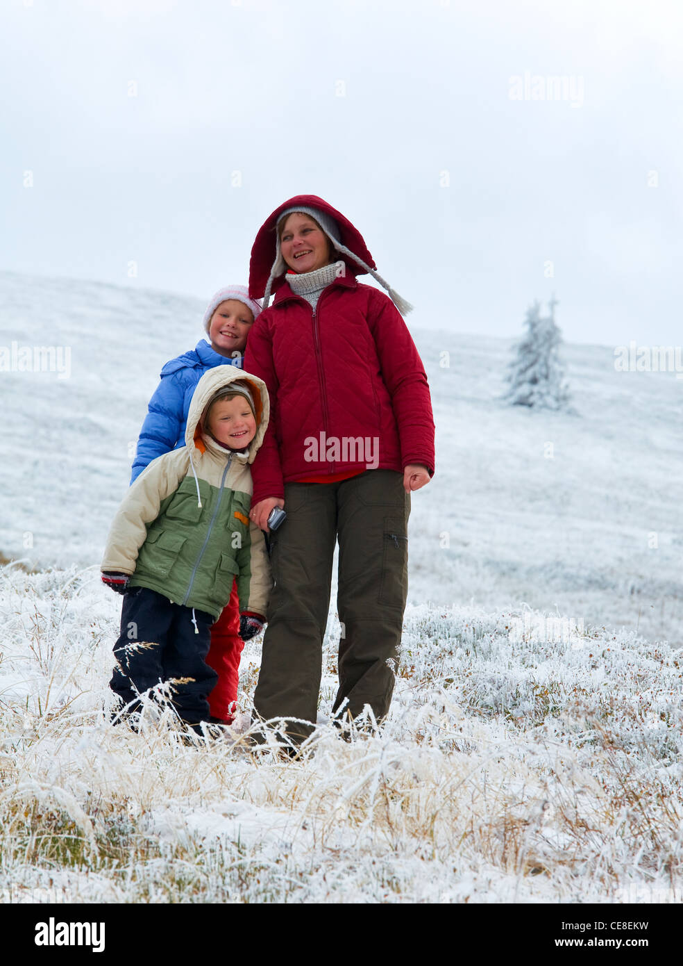 La famiglia (madre con bambini) camminare e giocare in autunno altopiano di montagna con la prima neve invernale Foto Stock