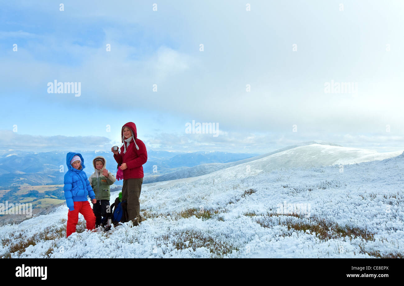 La famiglia (madre con bambini) bere il tè caldo in autunno altopiano di montagna con la prima neve invernale Foto Stock