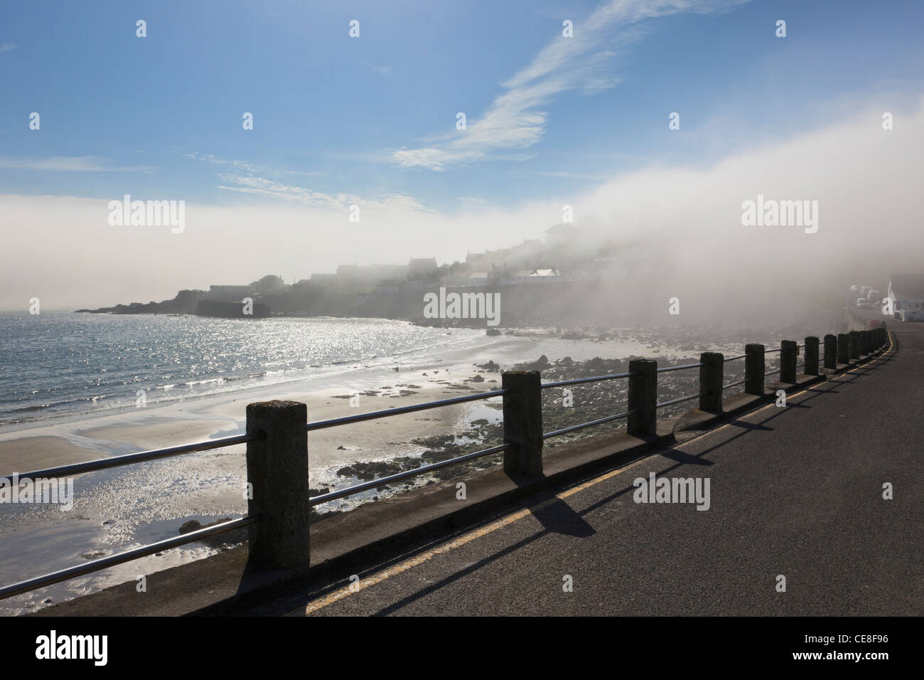 Coverack, Cornwall, Inghilterra, Regno Unito. Il lungomare e la spiaggia con il mare di nebbia sul villaggio di operazioni automatiche di fine campo Foto Stock