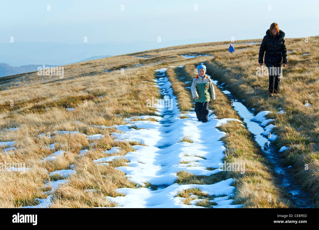 La famiglia (madre con bambini) a piedi in autunno altopiano di montagna con la prima neve invernale Foto Stock
