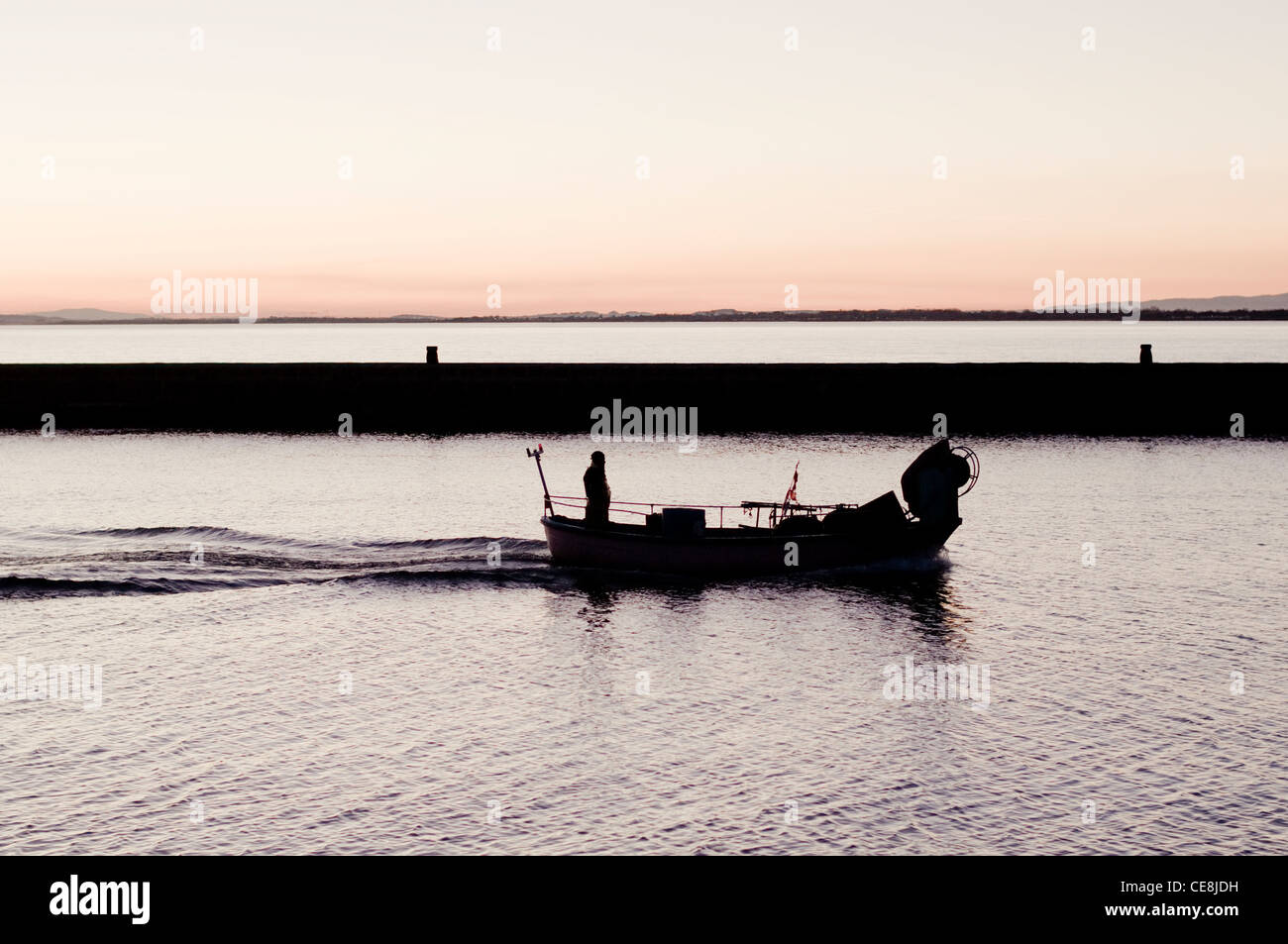 Un uomo in barca da pesca nella luce della sera, tornando al Porto di Grau d Agde, Herault, Languedoc, Francia. Foto Stock