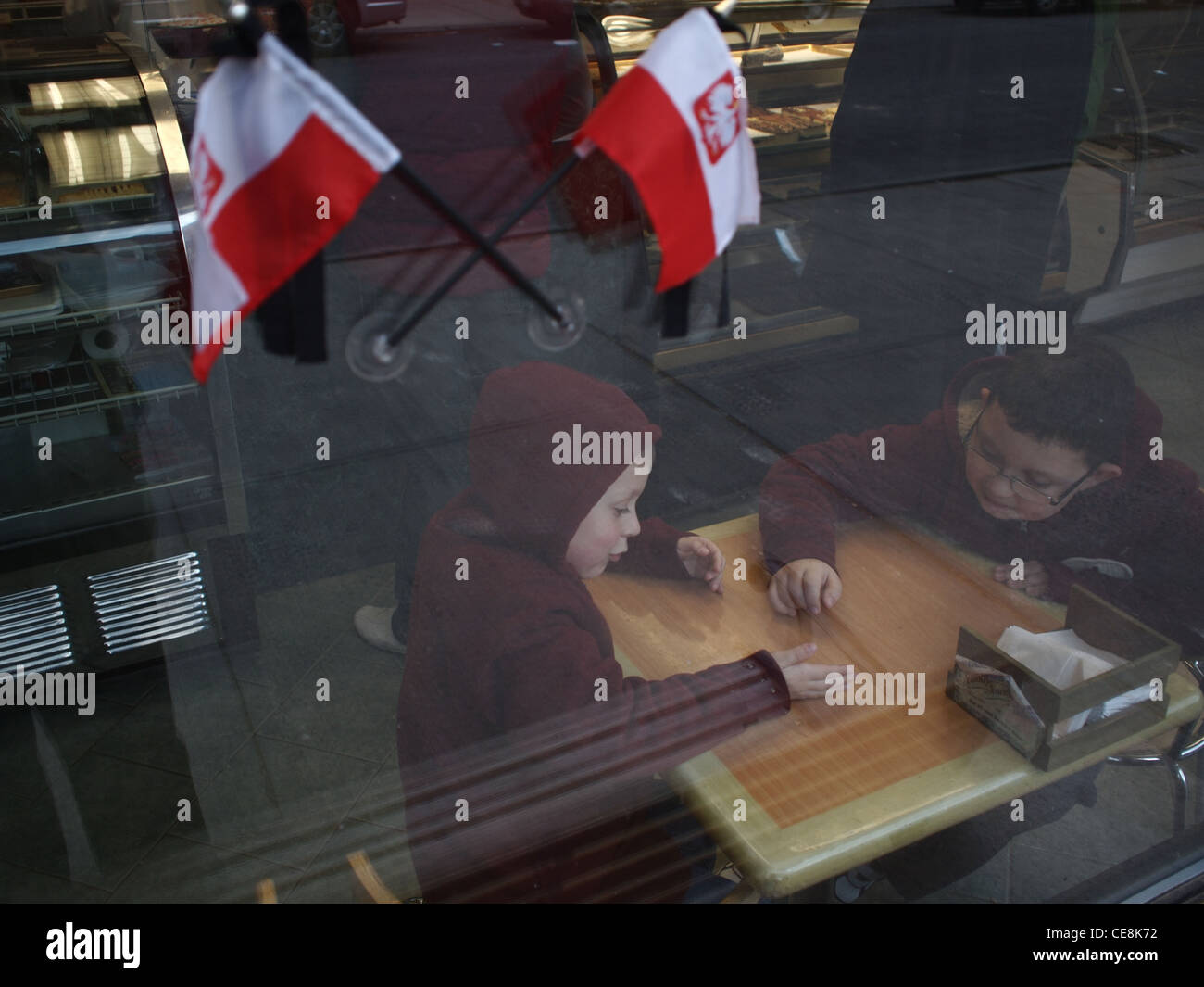 Due ragazzi giocare in polacco panetteria con bandiere polacche nella finestra, Brooklyn, New York Foto Stock