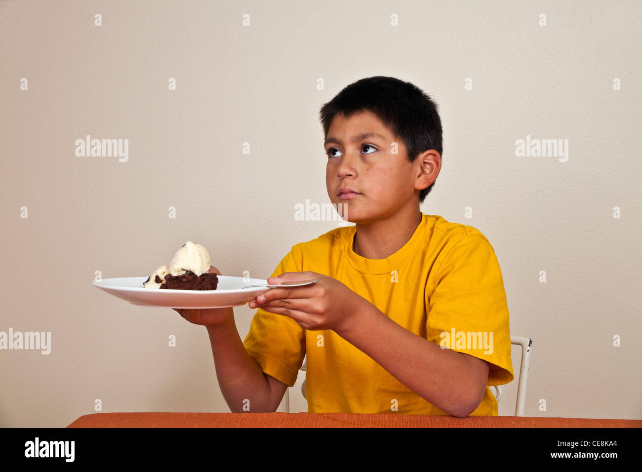Forte voluta testardo 10-11 anni ragazzo ispanico non vuole mangiare multi diversità razziale razziale multiculturale culturale. Foto Stock