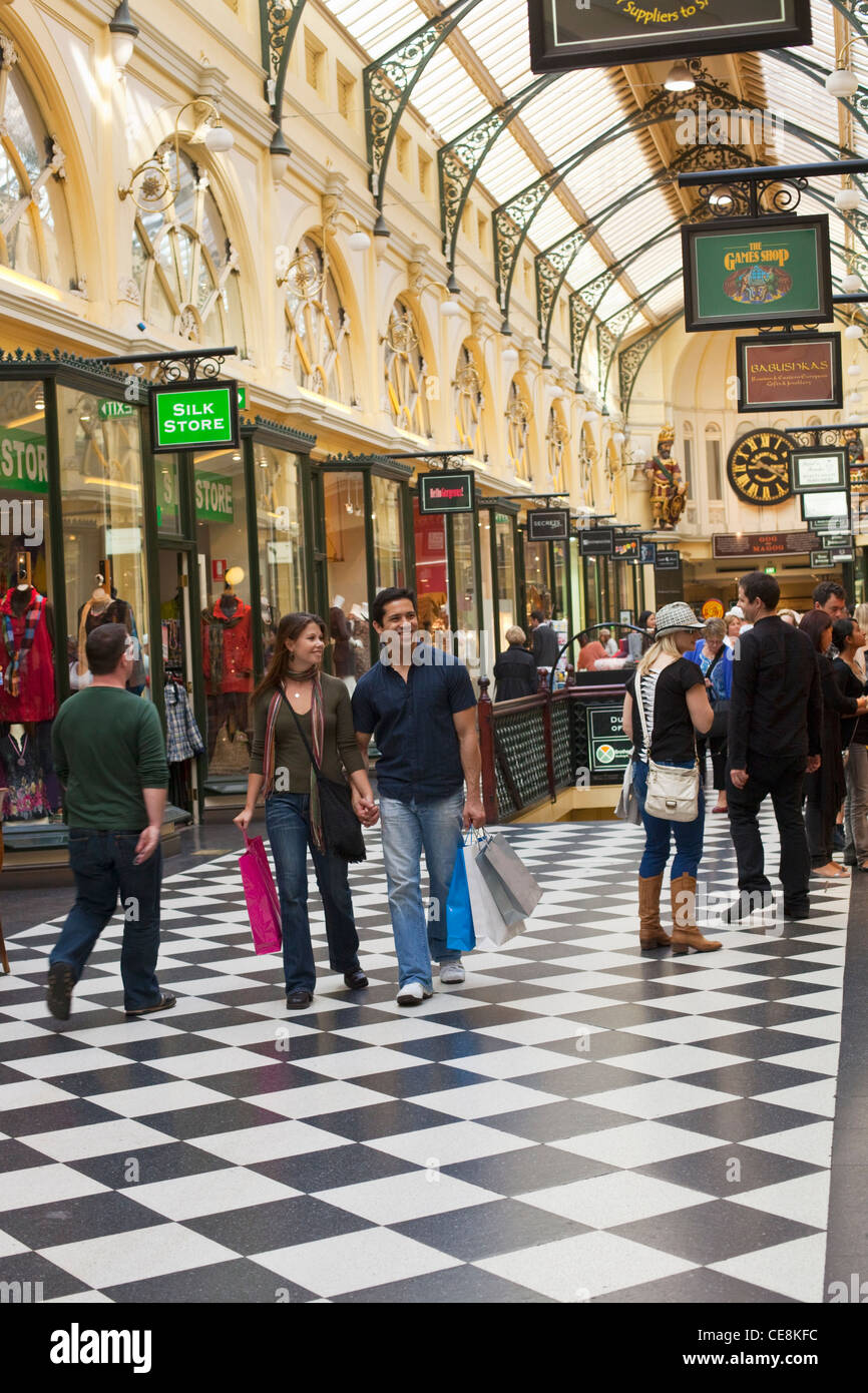 Giovane a piedi con le borse della spesa in arcade. Melbourne, Victoria, Australia Foto Stock