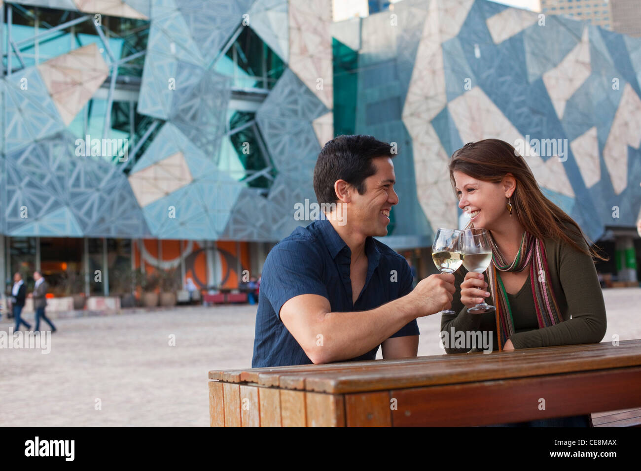 Coppia giovane godersi drink presso un bar all'aperto. Federation Square, Melbourne, Victoria, Australia Foto Stock
