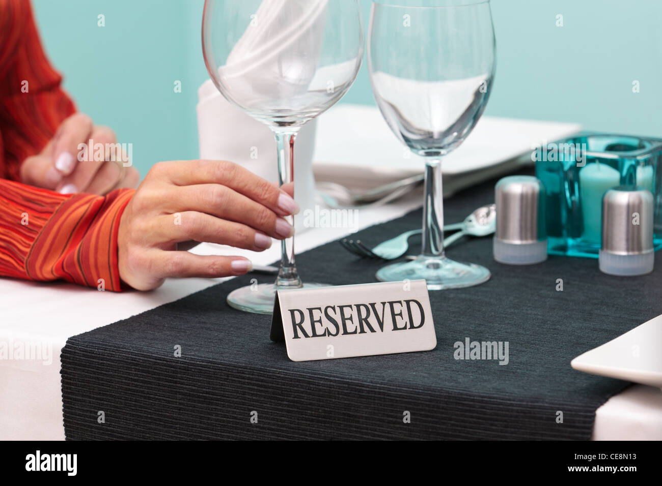 Foto di un womans mano che tiene un bicchiere a un tavolo riservato in un ristorante Foto Stock