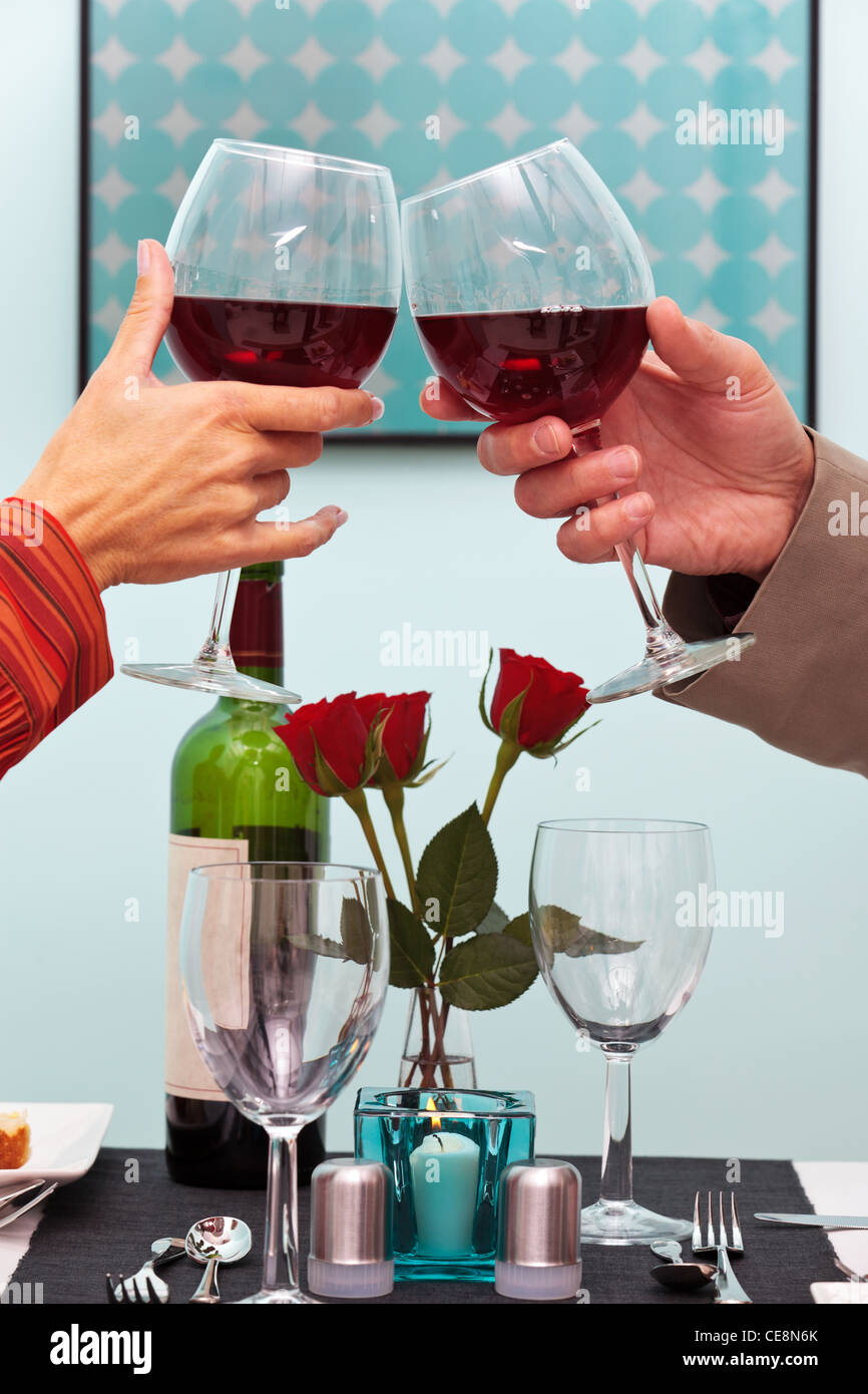 Foto di coppie mani tostare i loro bicchieri di vino rosso al di sopra della tavola in un ristorante Foto Stock