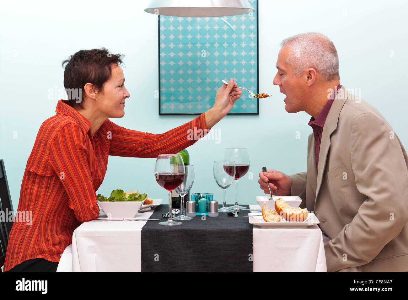 Foto di una moglie lasciando il marito provare il suo cibo in un ristorante. Foto Stock
