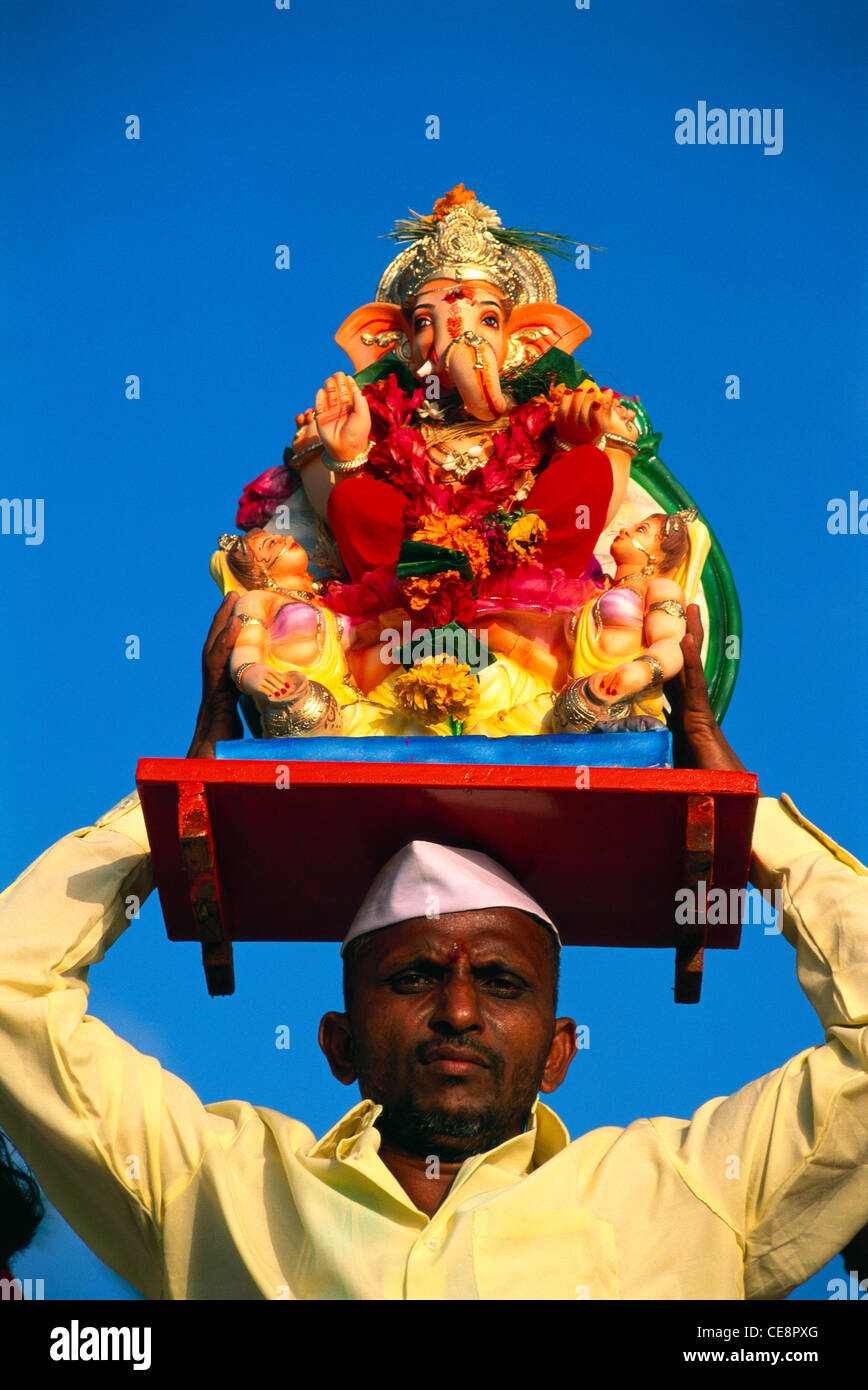 Uomo con statua sulla sua testa del dio indiano Ganesh sul Festival ganpati testa di elefante Signore immersione bombay mumbai india Foto Stock