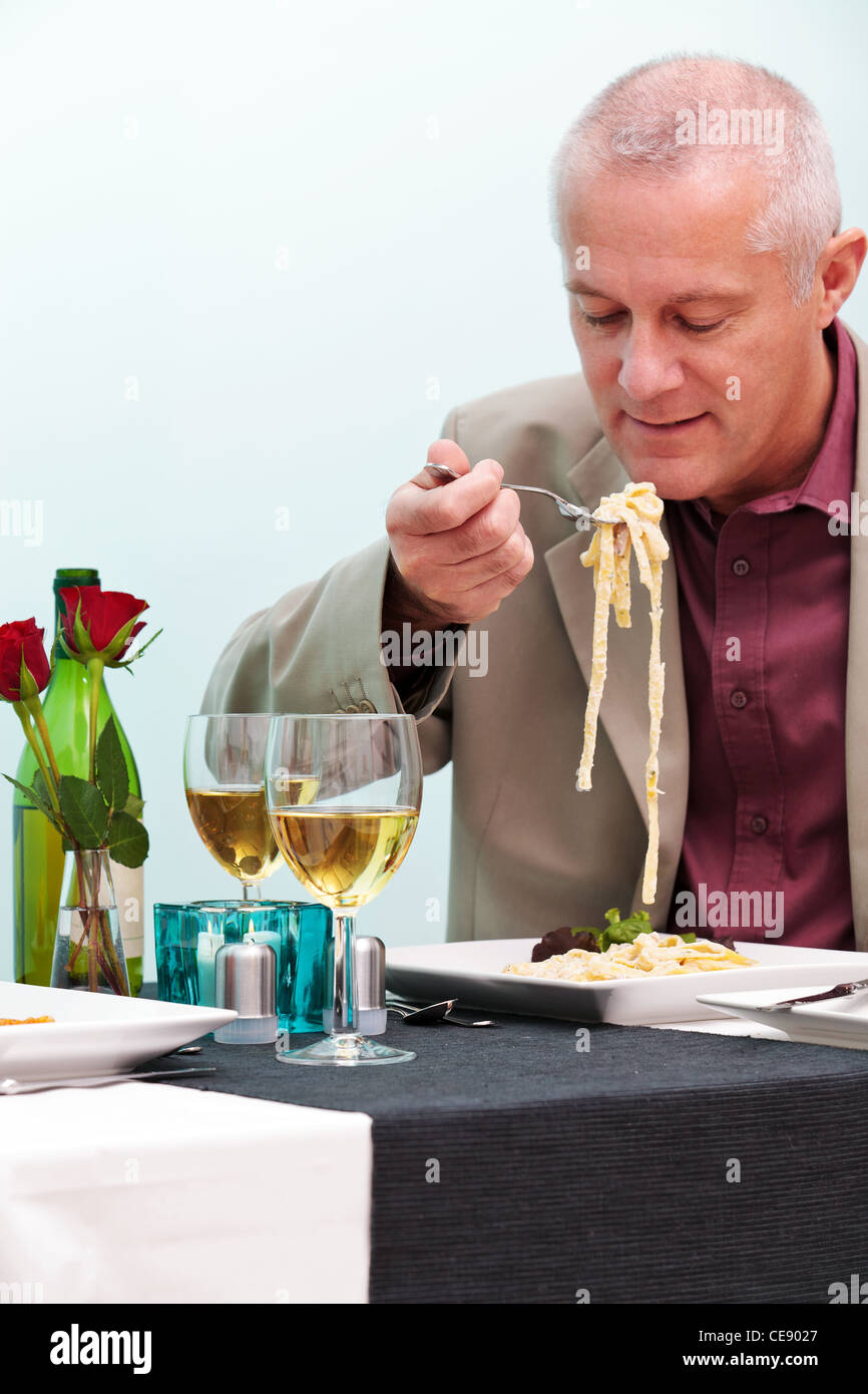 Foto di un uomo maturo di mangiare la pasta in un ristorante. Foto Stock