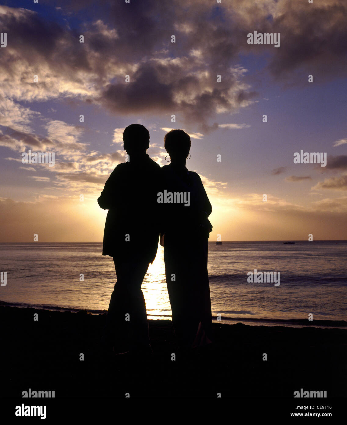 Scatto di una coppia romantica guardando un tramonto sul mare da un'isola tropicale Foto Stock