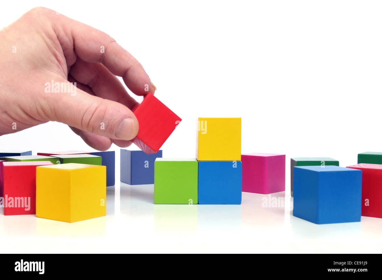 Mano umana e giocattolo multicolore blocchi su sfondo bianco Foto Stock