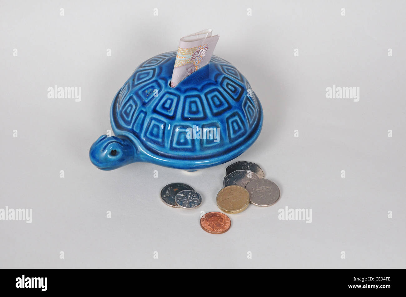 Tartaruga scatola di denaro con dieci pound nota e monete sterling Foto Stock
