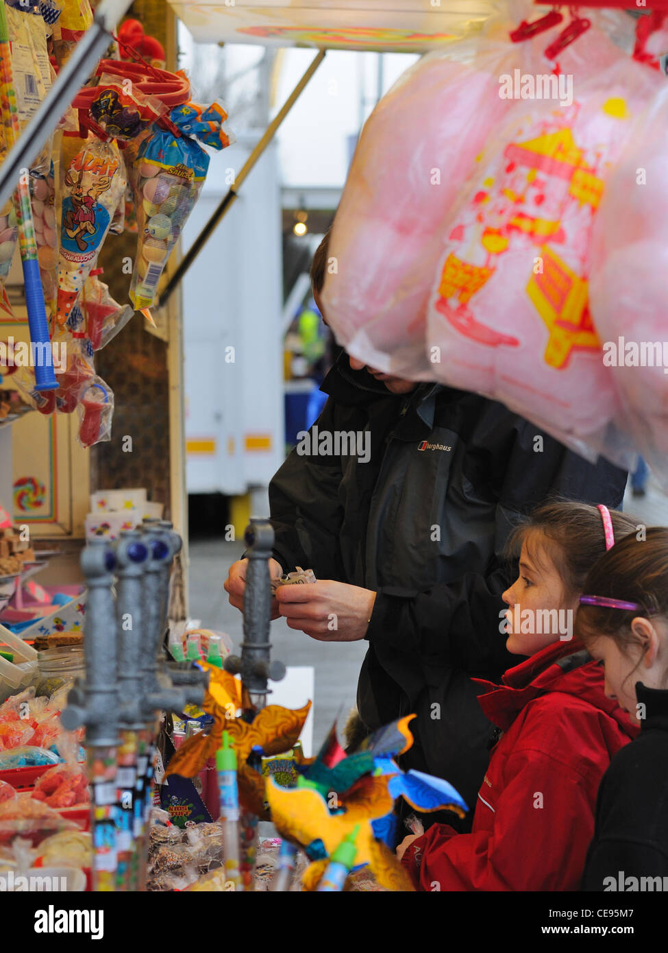 Una giovane ragazza si erge con speranza come suo padre paga per dolci in un mercato in stallo Foto Stock