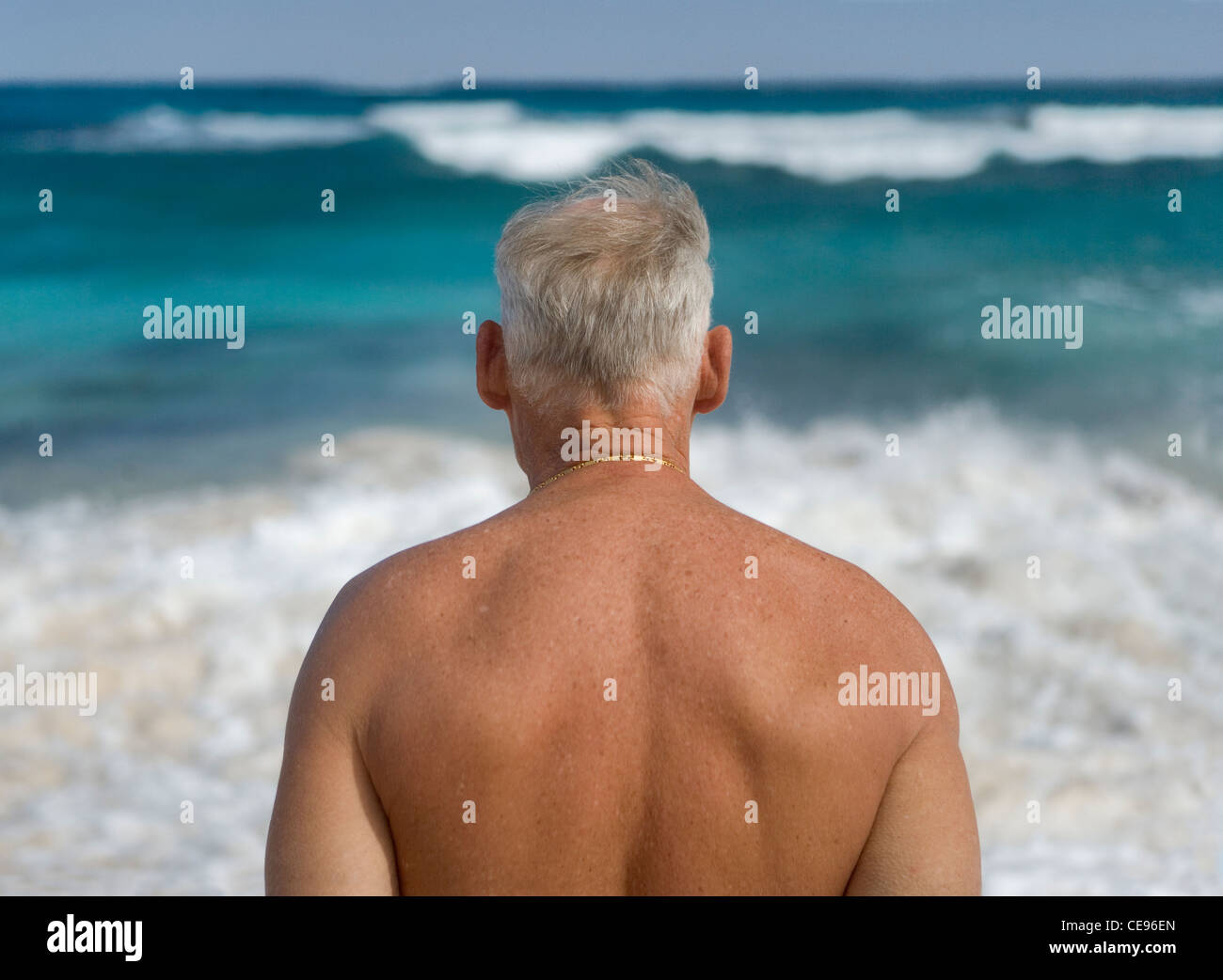Un uomo senior presso la spiaggia guarda al mare. Foto Stock