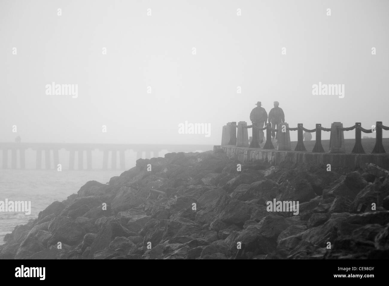 Una coppia di anziani a piedi nella fitta nebbia Foto Stock