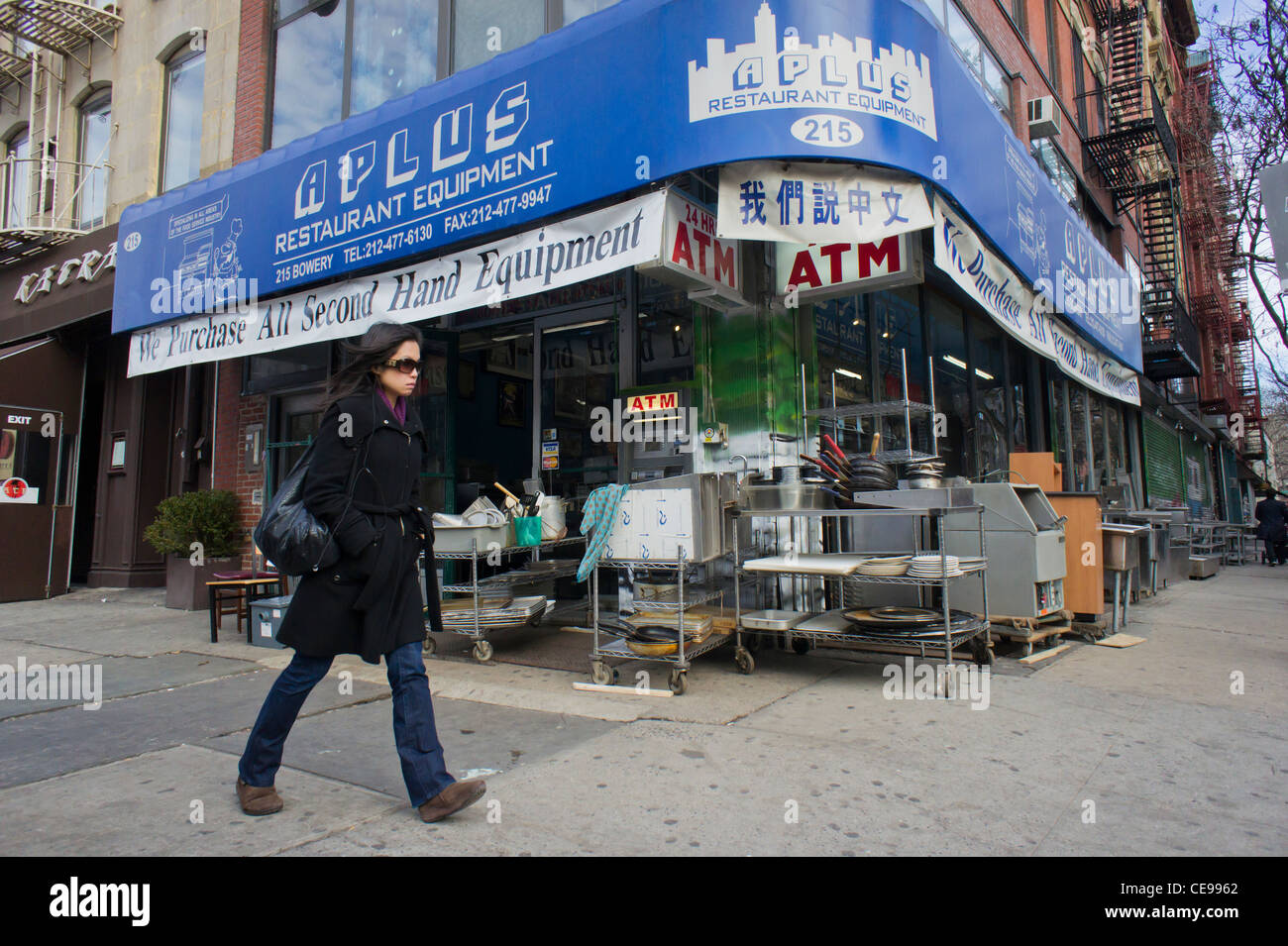 Una donna cammina davanti a un ristorante venditore di alimentazione sulla modifica di Bowery a New York Foto Stock