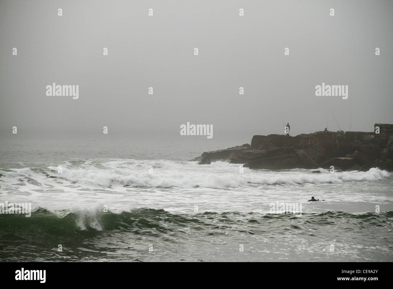 I Pescatori e surfisti in Sao Pedro spiaggia, grande Lisbona, Portogallo Foto Stock