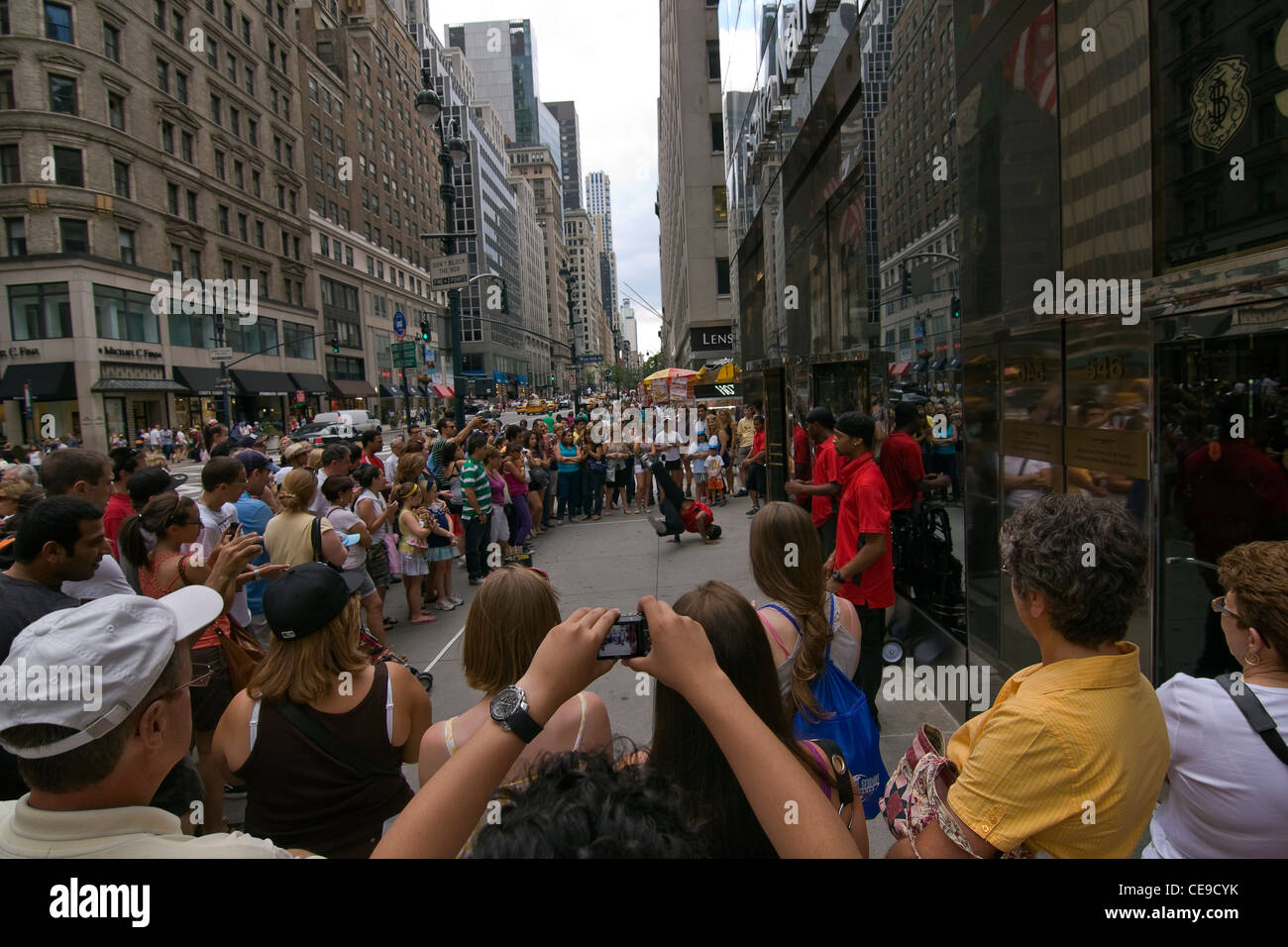 Decine di persone guardare quattro americano africano di uomini in camicie rosse eseguire un break dance routine sul 5th Ave marciapiede in NYC Foto Stock