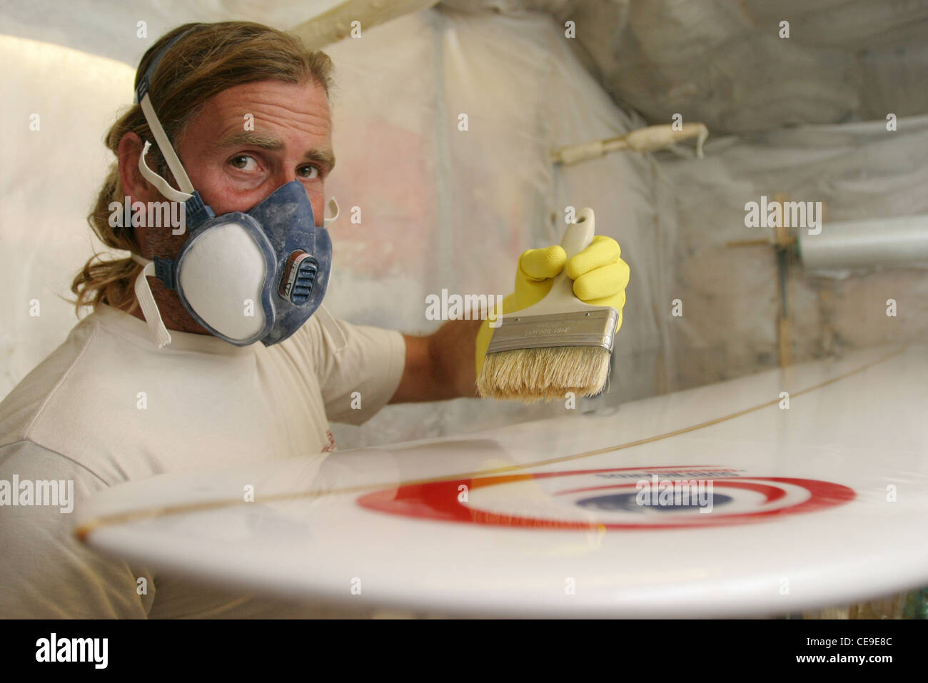 Tavola da surf shaper Chris budella Griffiths bicchieri una tavola da surf nella sua fabbrica di Gower, Galles del Sud Foto Stock