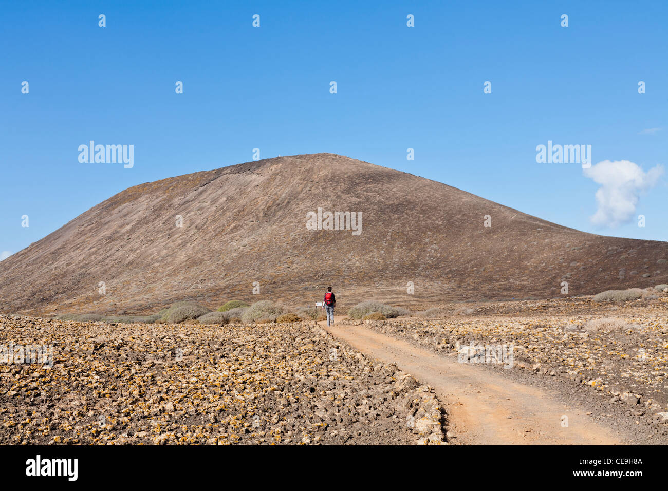 Una donna che cammina verso la caldera vulcanica sull isola di Lobos, vicino a Corralejo, Fuerteventura, SPAGNA Foto Stock