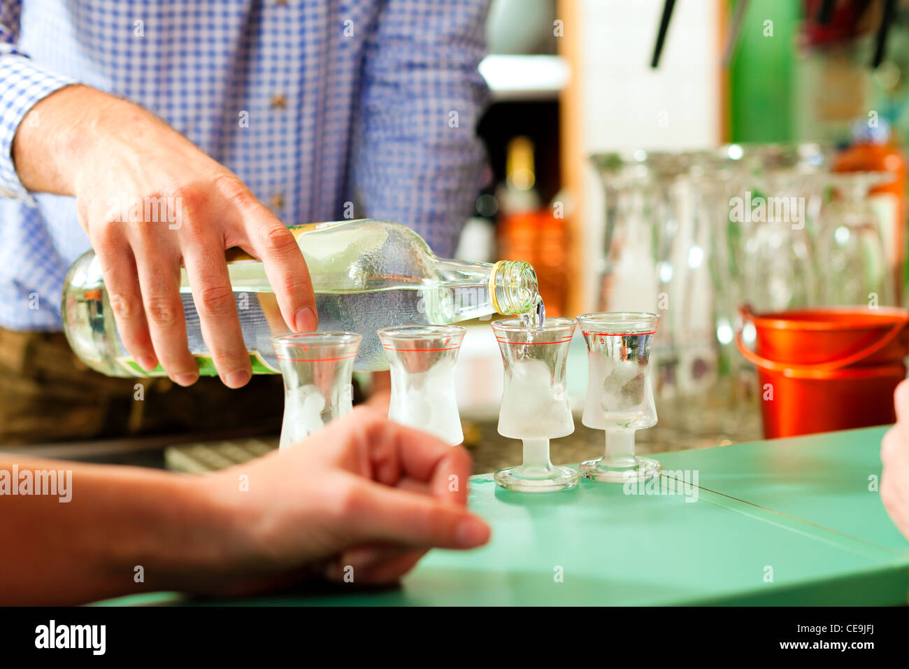 Barman versando liquori in bicchieri in piedi sulla barra Foto Stock