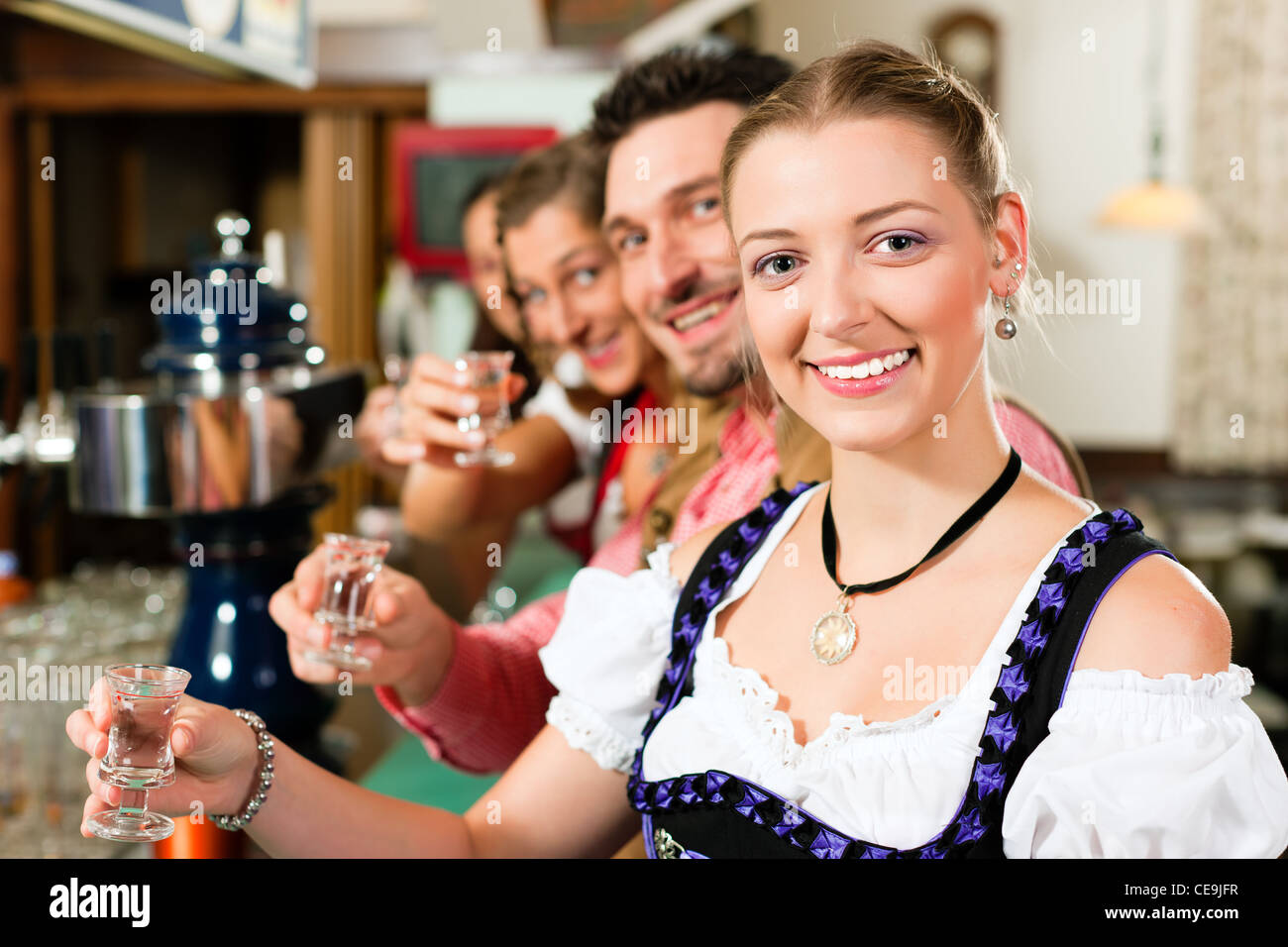 Persone in Baviera Tracht bere liquore duro in un pub e divertirsi Foto Stock